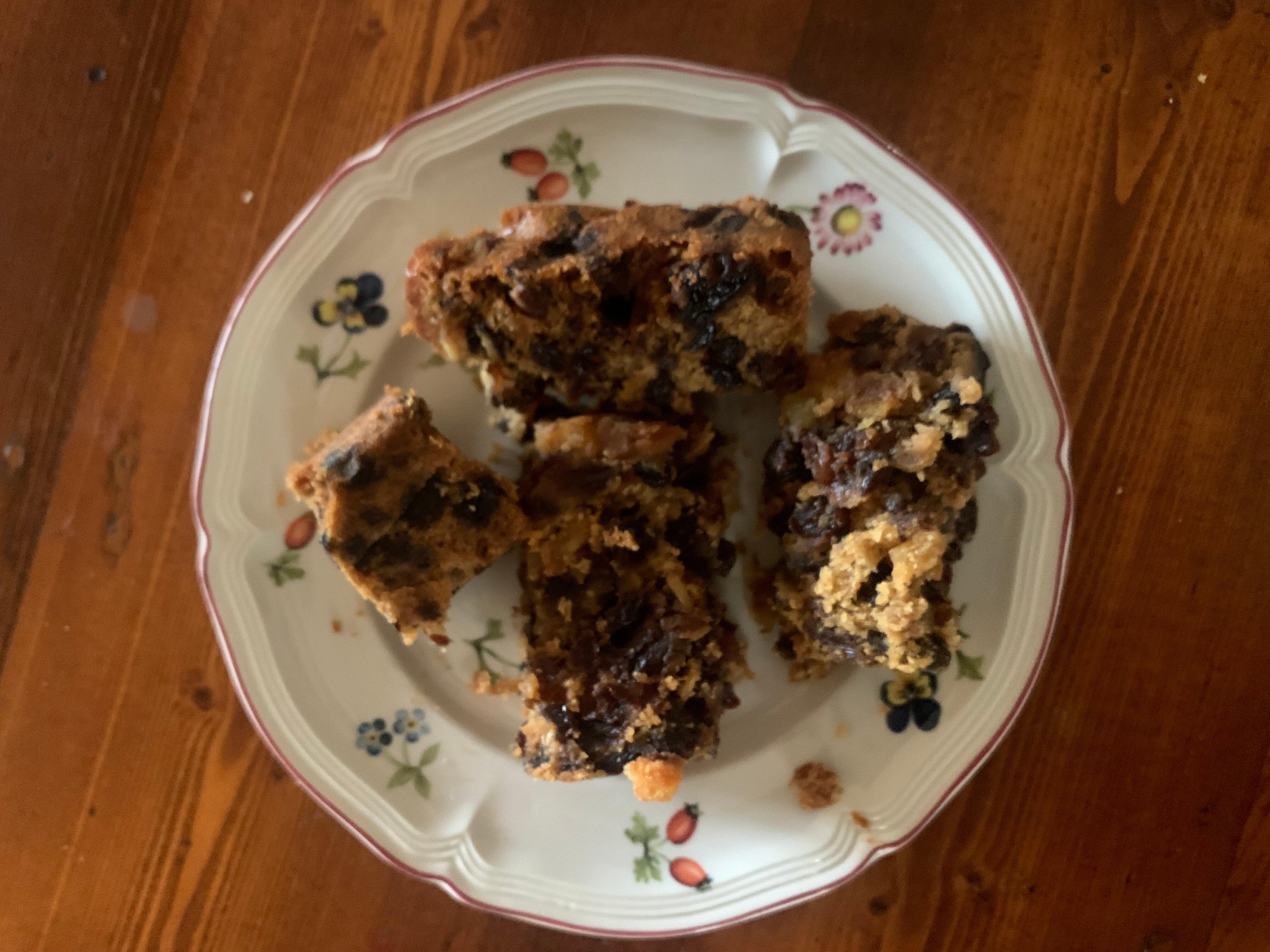 Various pieces of fruit cake on a small white plate with floral motifs