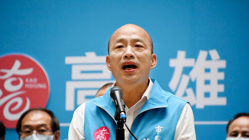 Mayor Han Kuo-yu speaks to the media wearing the blue vest of his party.