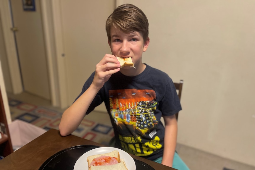 A boy in a Dr Who T-shirt is eating.