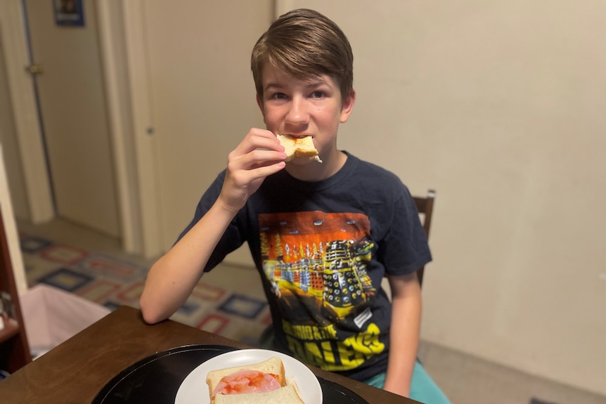 A young boy in a Dr Who t-shirt eats.