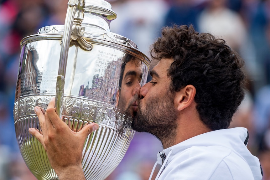 Matteo Berrettini kisses a large silve trophy