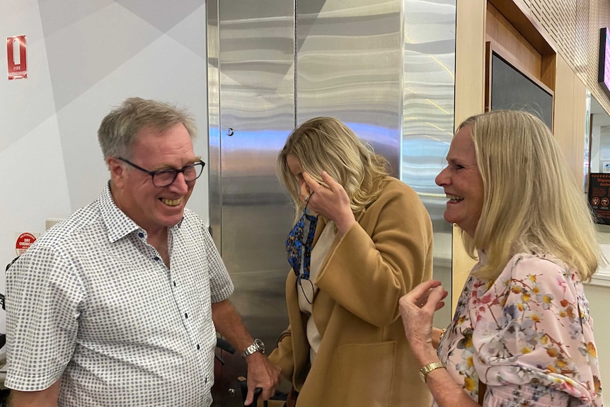 Older man and woman reunite with their daughter at airport terminal