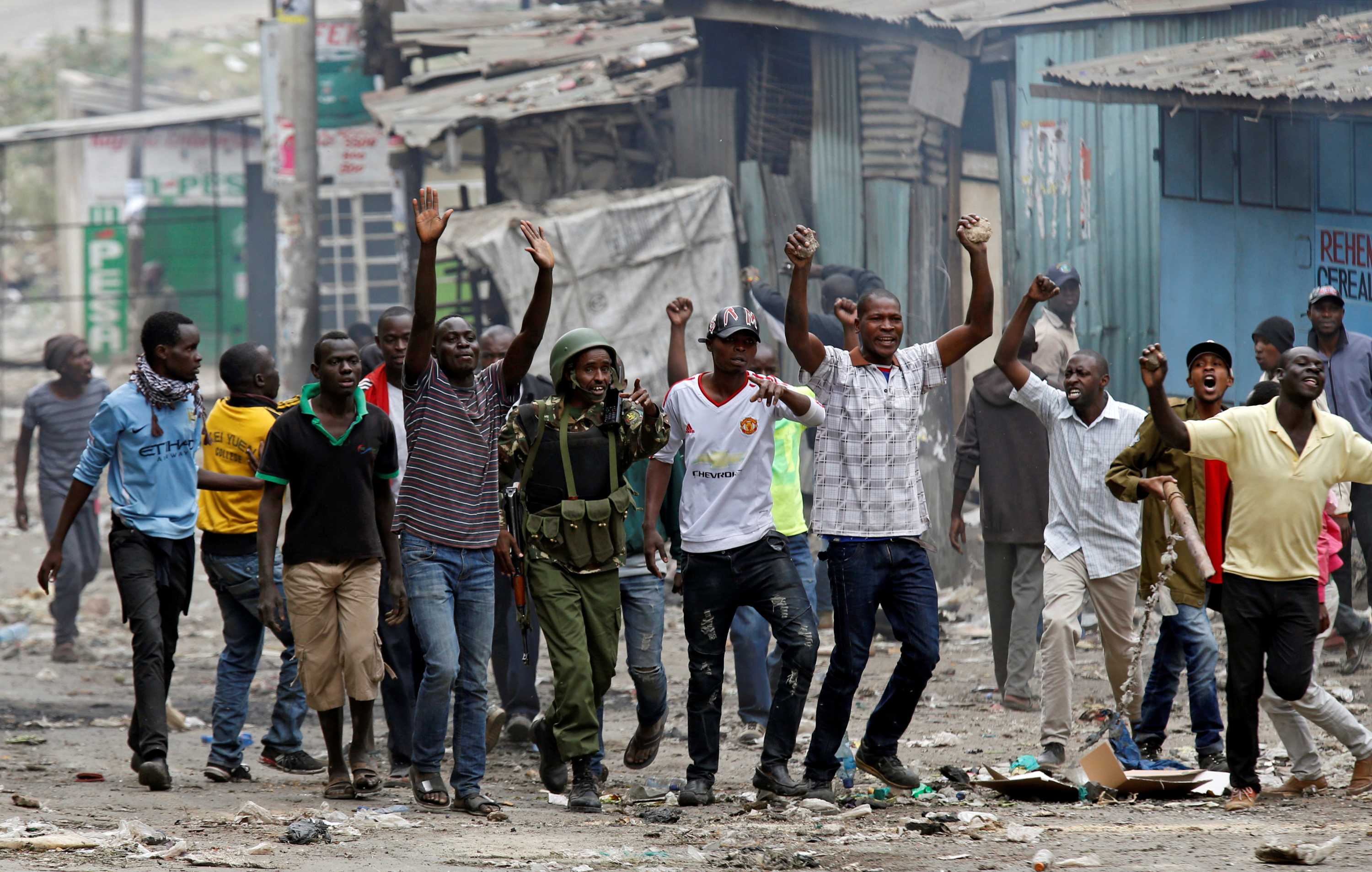 A group of men walk forward with their hands in the air.