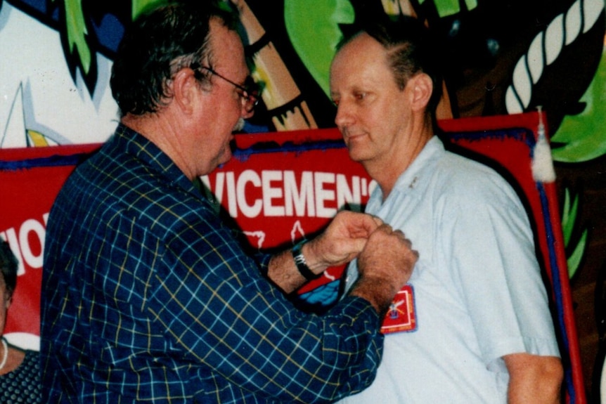 A older photo from 2002 of a medal being pinned on a man.