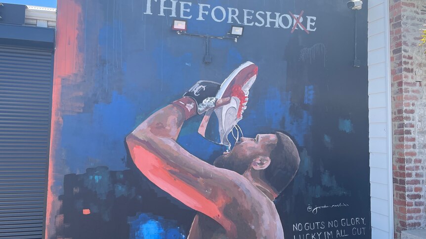 Painting of shirtless boxer holding up sports shoe with liquid falling into his mouth  