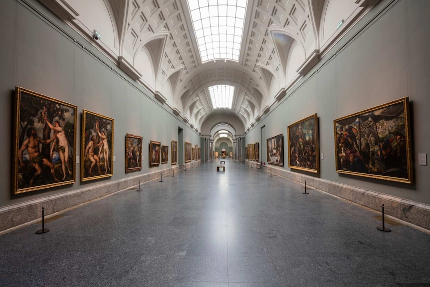 an empty hall of the Prado Museum in Madrid with paintings on the walls