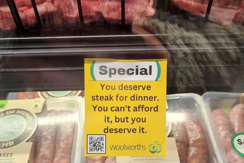 A photoshopped Woolworths sign in the meat section says "you deserve steak for dinner. You can't afford it but you deserve it"