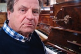Eric Hawkes sitting in his North Hobart piano restoration workshop.