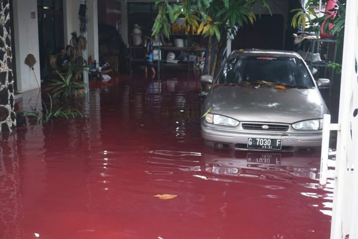 A house and carport inundated by the blood-red flood waters