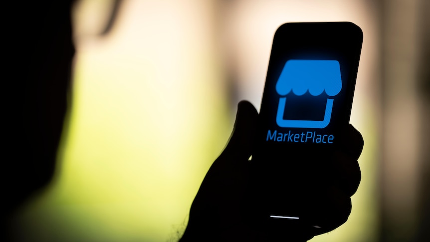 A person holding a phone displaying the Facebook Marketplace logo