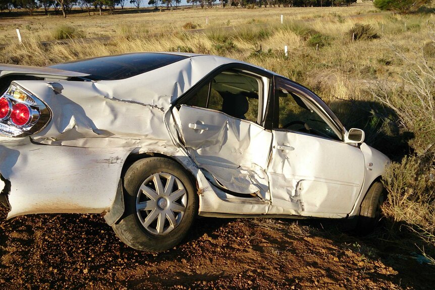 A badly damaged white car in field