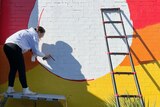 A woman spraying paint on a wall.