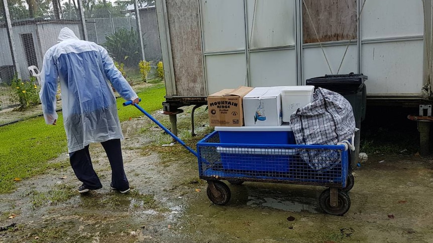 A man moves goods on a trolley around a decommissioned section of the Manus Island detention centre.