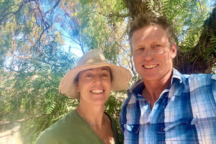 A man and woman standing under a tree.