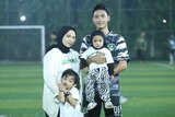 A family of four standing in the middle of a soccer field.