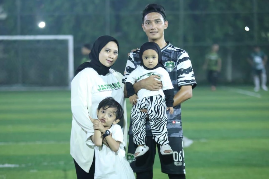 A family of four standing in the middle of a soccer field.