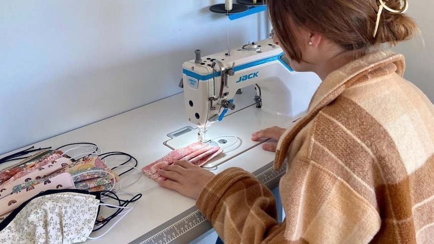 Monique sitting at her desk sewing.