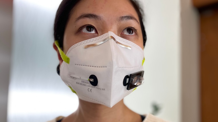 A woman wearing an N95 face mask with small attached sensors