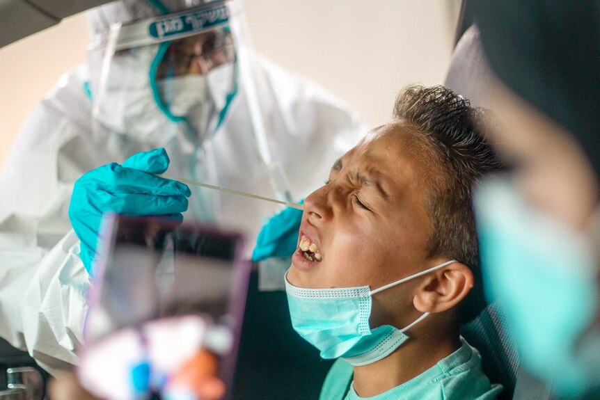 A young boy grimacing as he gets a COVID-19 swab up the nose