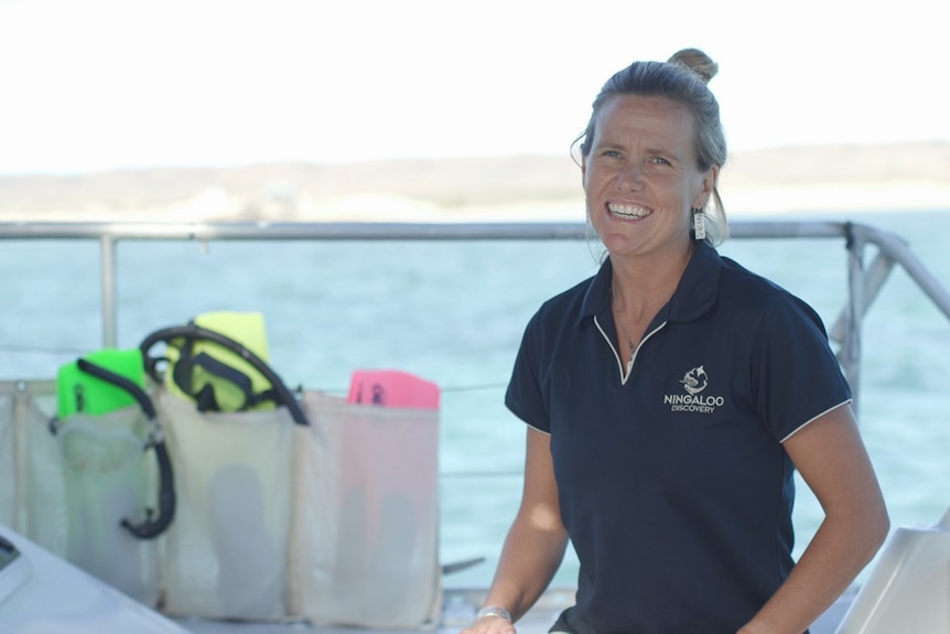 A young woman smiling on a boat, out at sea.