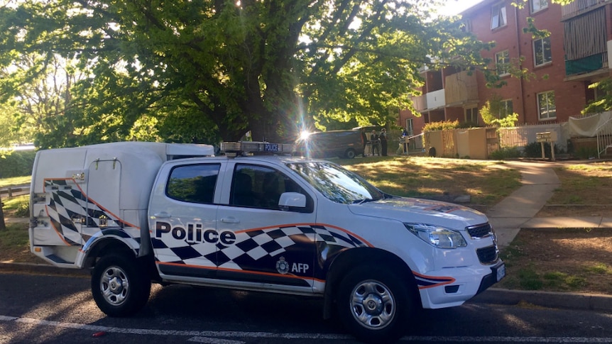 A police wagon parked outside a brick unit block in Watson.