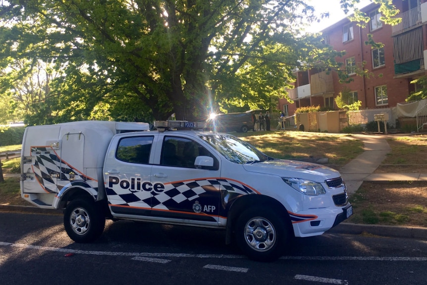 A police wagon parked outside a brick unit block in Watson.