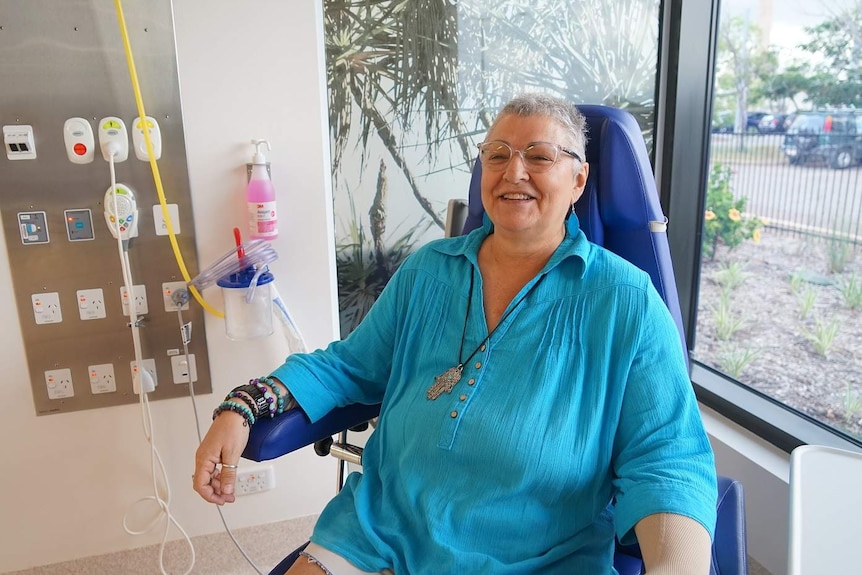 A lady sitting in a chair getting cancer treatment.