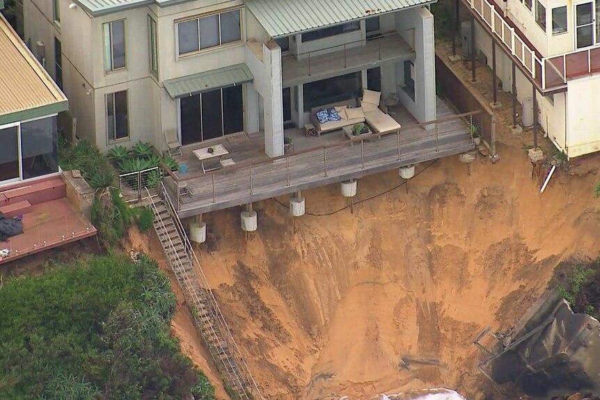 An aerial view of a home's veranda foundations exposed after the whole front yard collapsed into the sea.