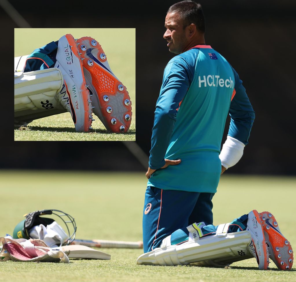 Usman Khawaja leans on his knees on a grass field. Inset close up of shoes with pen writing.