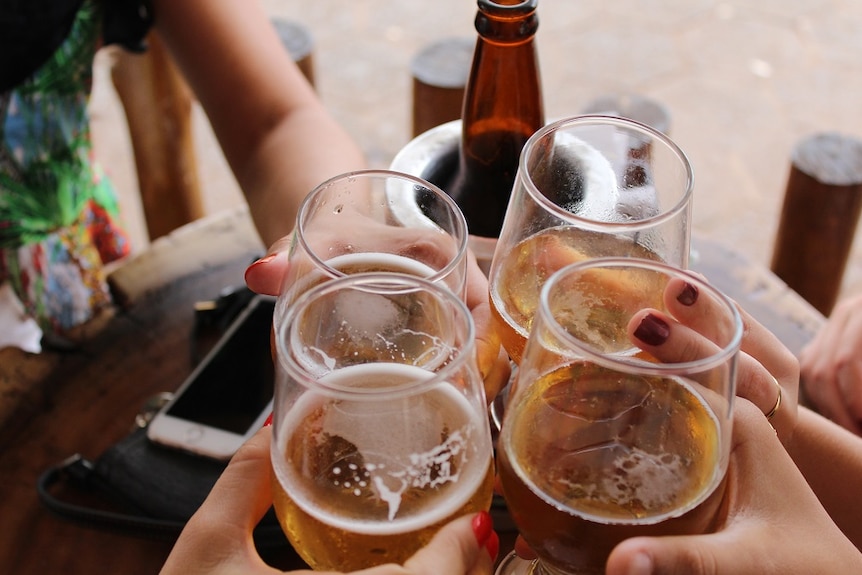 A person holds glasses full of alcoholic drinks.