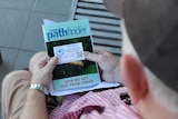 Elderly man looking at AA information on a pamphlett.