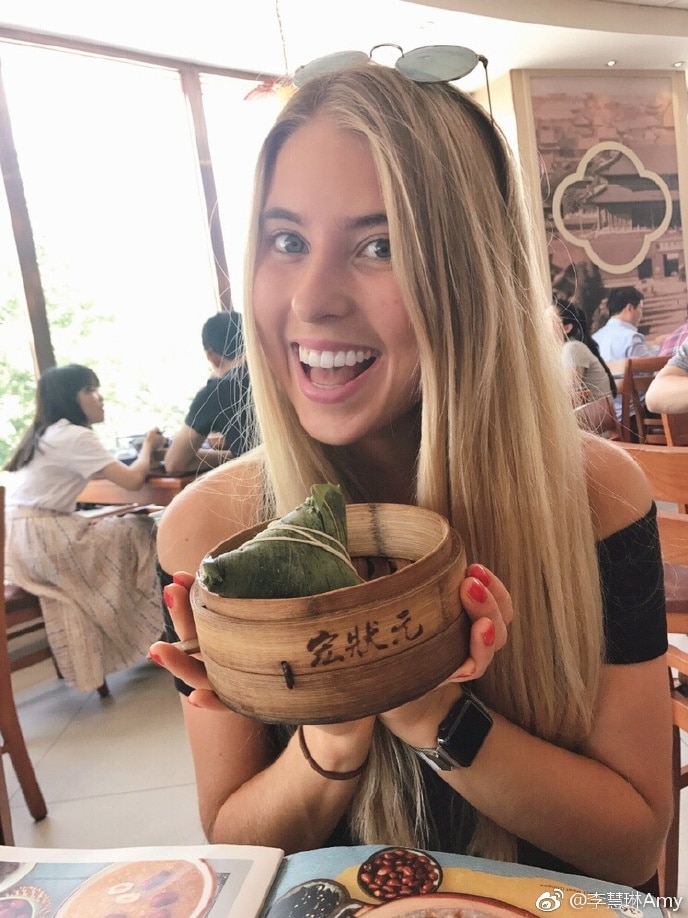 Amy Lyons smiles in a restaurant holding a dish