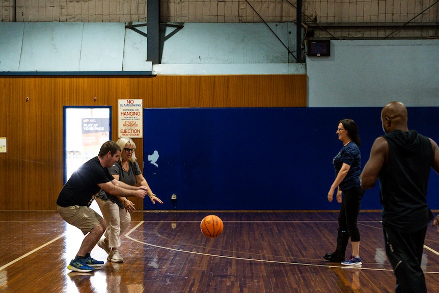 Four people on the basketball court playing vision impaired basketball.
