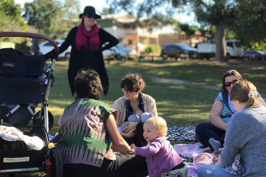 A group of mothers sitting around with babies in a park