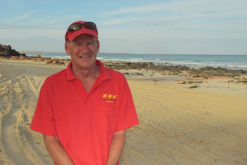 Man stands at beach with red shirt