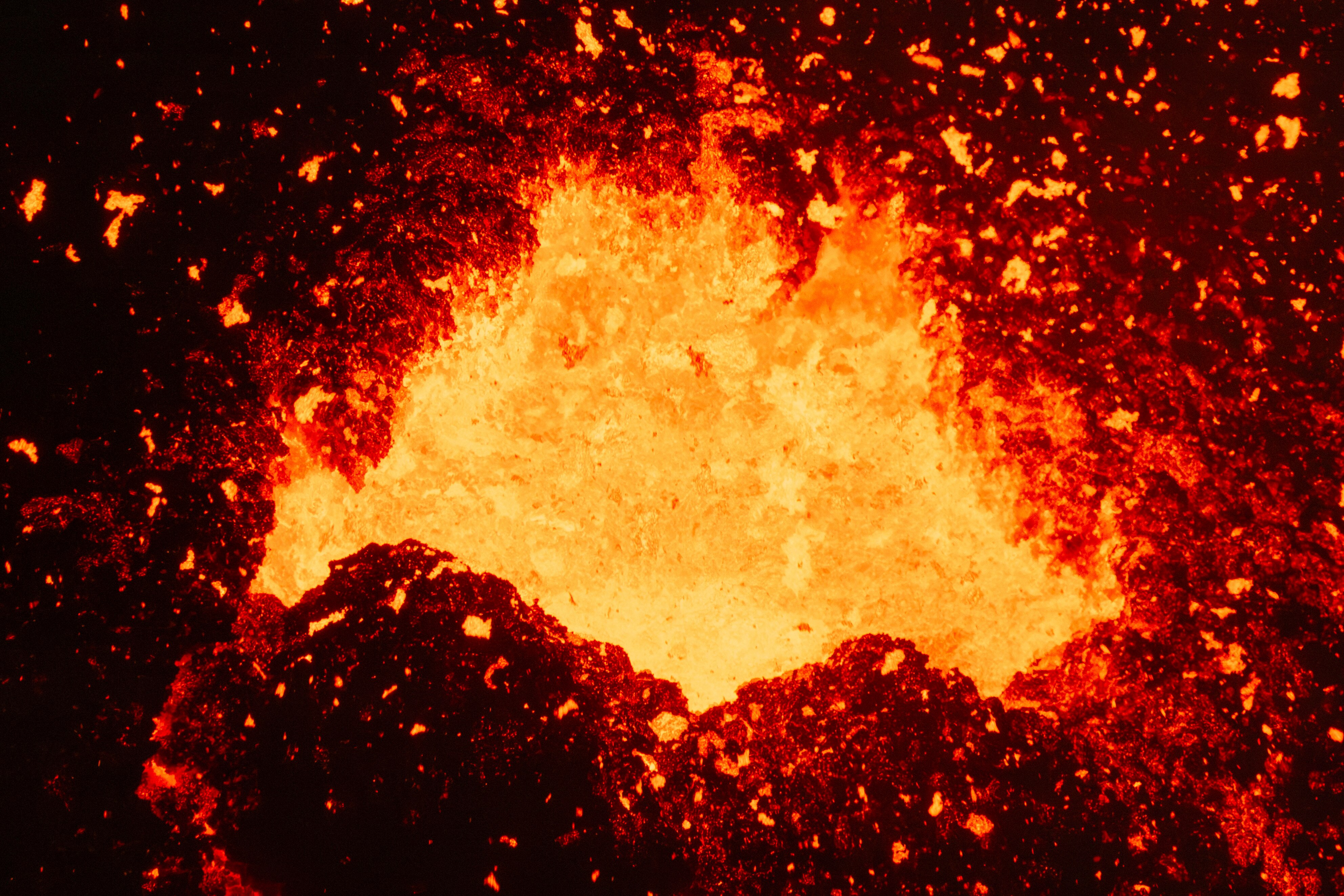 A close up of lava flying out of the mouth of an active volcano.