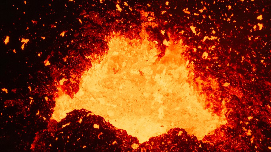 A close-up of lava flying out of the mouth of an active volcano.