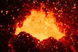 A close-up of lava flying out of the mouth of an active volcano.
