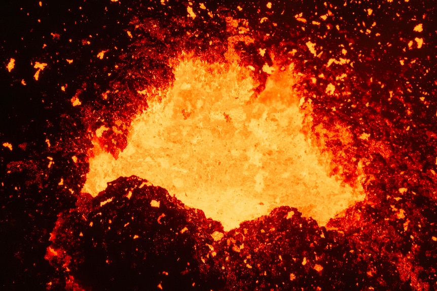 A close up of lava flying out of the mouth of an active volcano.