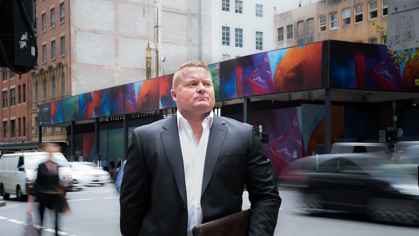 Patrick O'Connor stands in front of a construction site on a city street