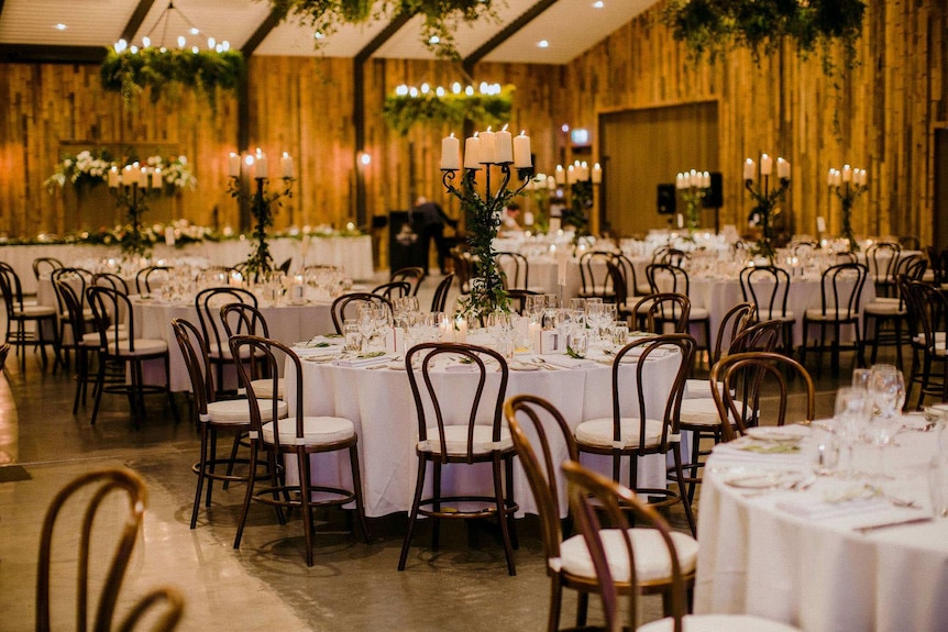 A lavishly decorated room with chairs and tables, candelabras and greenery.
