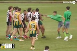 A still from a AFLNT match which shows multiple players standing around, one players arm is holding the shirt of an umpire.