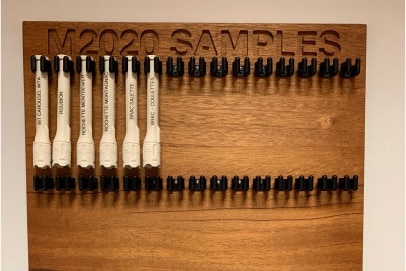 Six white plastic test tubes hanging on wooden plaque with the words 'M2020 Samples'