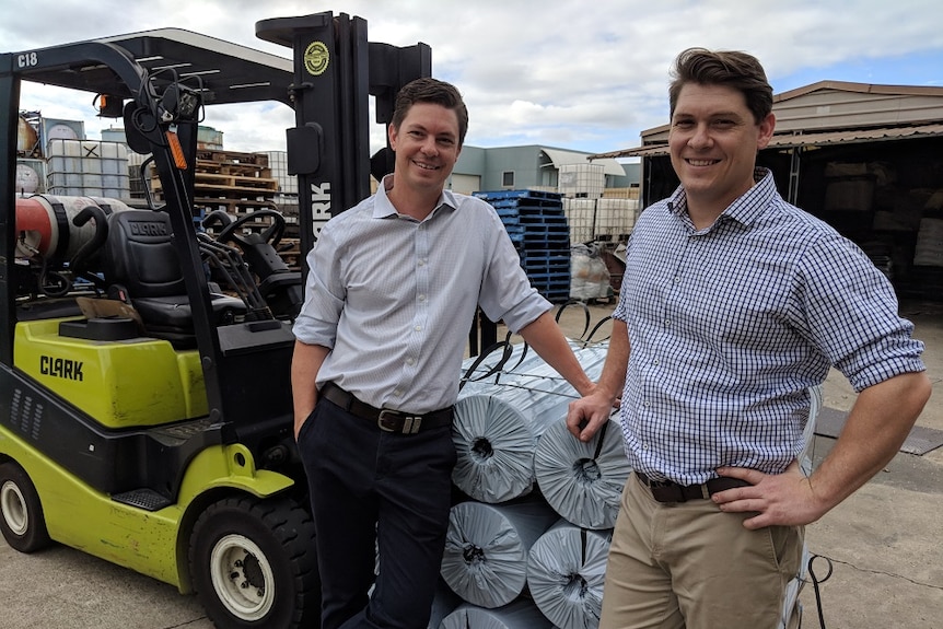 Mark and Rob Trenchard leaning on a stack of solar shrink mulch film roles at their Hydrox Technologies factory