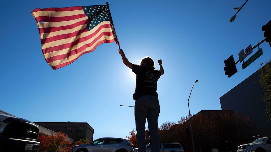 A woman waving an American flag on a street