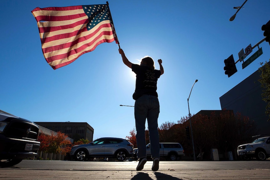 A woman waving an American flag on a street