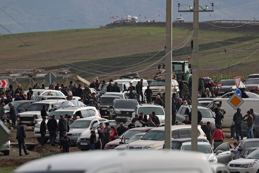 Cars queued in front of an empty field. 