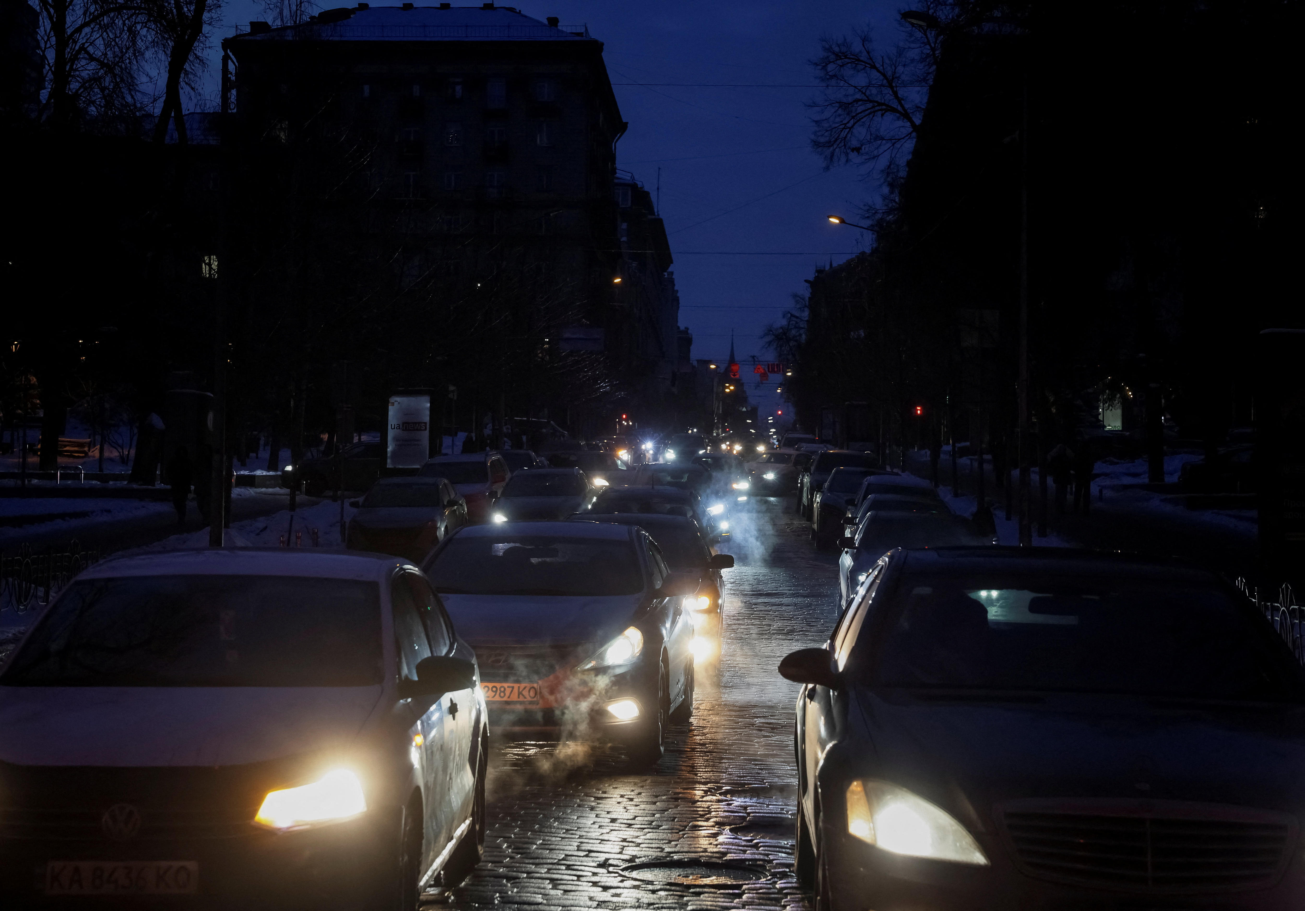 Coches en una calle por la noche con luces apagadas.