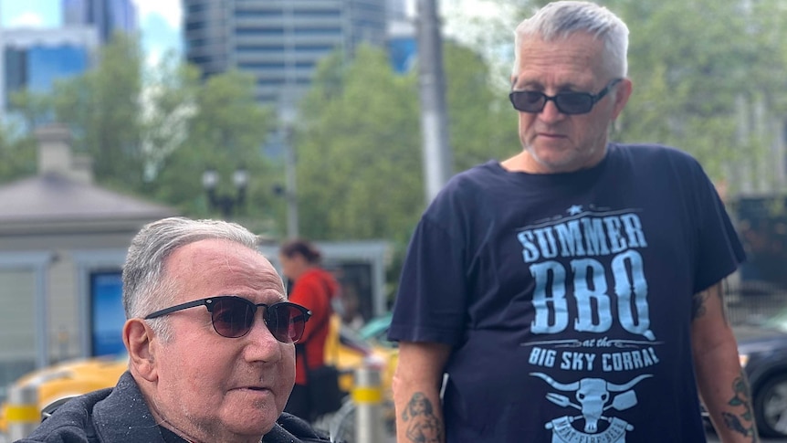 Two elderly men standing in a city street.