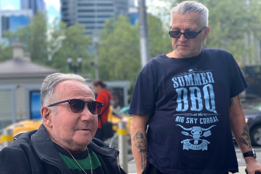 Two elderly men standing in a city street.